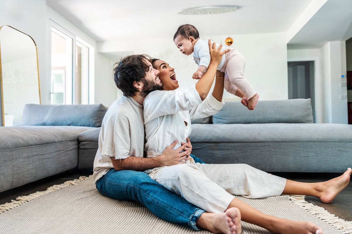 Multiracial husband and wife playing with cute little daughter at home